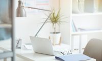 Close-up of workplace with laptop and folder on it at light modern office